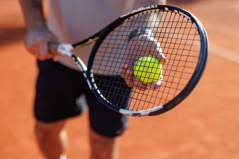 Hands holding a tennis racket on court – Le Sentier des Pins, Le Village des Lavandes