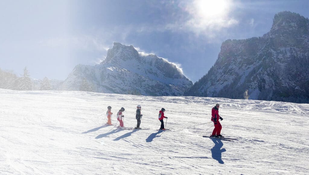 Man is skiing with four children in a line behind him in… — Le 1850 à Risoul