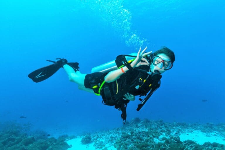 Female scuba diver signalling underwater – Diving