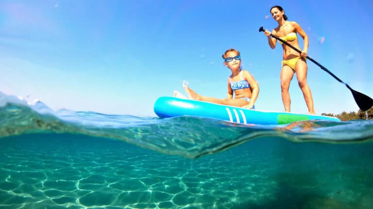 Mum and daughter paddleboarding on a sunny day